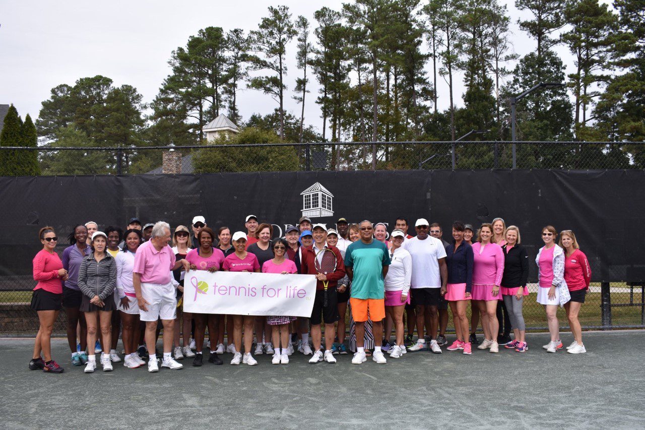 A group of people standing on top of a tennis court.